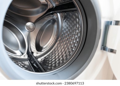 View into washing machine drum inside with stainless steel drum interior shows household equipment for cleaning clothes with dry cleaner and front loader for easy housework laundromat machine empty