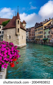 view of the island's medieval palace in the middle of the river that runs through the center of Annecy in France with flowers in the foreground - Selective focus

