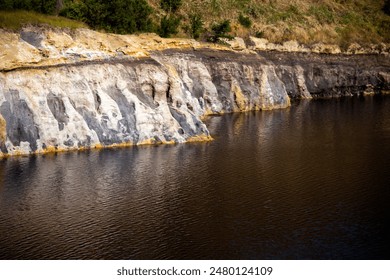 View of the jagged rock face with mineral residues at the edge of the lake, Solfatara locality, Pomezia, Rome, Italy - Powered by Shutterstock