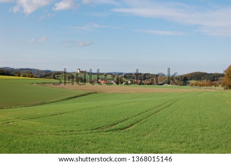 Similar – A tractor turns mown hay in a field in a small community