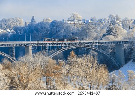 View to the Kirchenfeld bridge with running red tram on winter snowy day in Bern, Switzerland