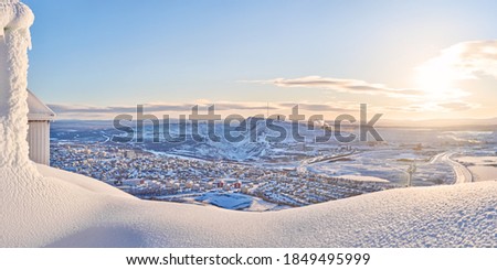 View of Kiruna city and the iron ore mine on the mountain Kiirunavaara seen from the snowy mountain peak Luossavaara.
