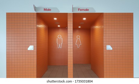 View of the lady and gentlemen's public toilet or bathroom entrance with bright orange tiles. - Powered by Shutterstock