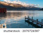 View of Lake Annecy and the mountains in autumn colors. In the foreground a pontoon awaits the boats.