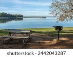 View of Lake Livingston reservoir located in the East Texas Piney Woods in Polk County, Texas, United States with wooden picnic table and barbecue grill