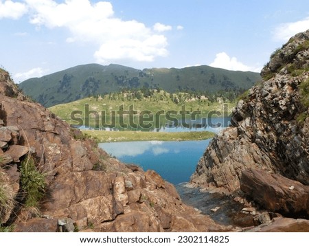 View of a lake and mountains from the top of a waterfall, framed by rock