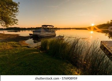 View of lake sunrise showing docked pontoon boat
