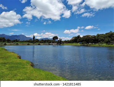 View Of Lake, Trees And Mountains In Simón Bolívar Metropolitan Park, Green Space And Entertainment And Sports Complex And Popular Public Park In The Middle Of Bogota, Colombia On Nice Sunny Day.