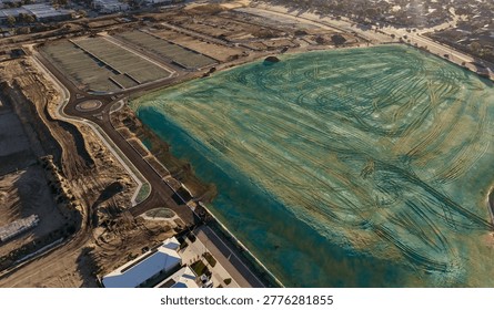 “Aerial View of Land Development with Artificial Lagoon, Construction Site and Urban Expansion