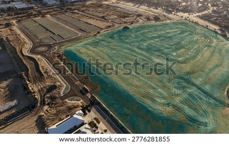 “Aerial View of Land Development with Artificial Lagoon, Construction Site and Urban Expansion