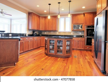 View Of A Large Upscale Kitchen With Hardwood Floors And Modern Fixtures. Horizontal Format.