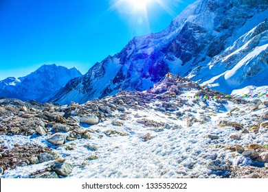 The view from the Larke Pass 5106 meters high peak at the Manaslu trekking path, Himalayas mountains, Nepal. Wind blowing prayers flags, snow, frozen ground and iced mountain peaks at the background.