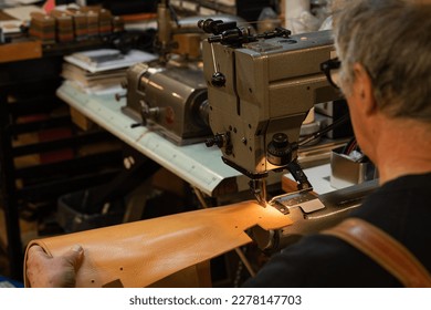 view of a leather craftsman’s shoulders sitting while sewing a leather back of a chair in his traditional workshop in the historic center of rome, italy - Powered by Shutterstock