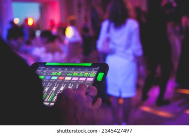 View of lighting technician with tablet, operator controlling sound and light during live event concert on stage show broadcast, technician with professional equipment, working on mixing console