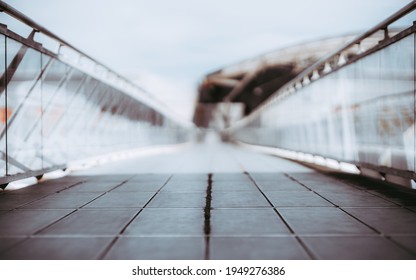 View Of A Long Bright Overhead Passage Or A Pedestrian Bridge Stretching Into The Distance, Glass Walls And Chrome Banister, Shallow Depth Of Field With Selective Focus On The Foreground Tiles