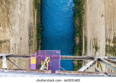 View Looking Down Over The Corinth Canal In Greece At An Empty Bungee Jumping Platform Below The Bridge That Is Painted Purple With Bright Blue Water And Steep Cliffs At The Bottom