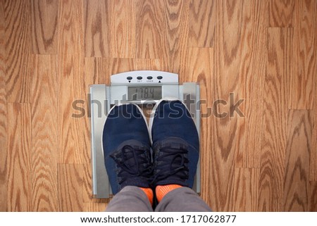 A view looking down at a person's own self standing on a scale on the floor.