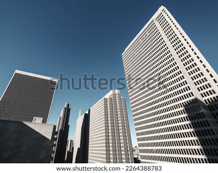 View looking up at monotone skyscrapers lit by morning sunshine standing out against a deep blue sky in San Francisco, USA