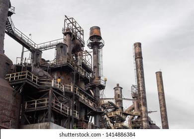 View Looking Up At Old Steel Mill Exterior, Layers Of Walkways, Stairs, And Smokestacks, Horizontal Aspect