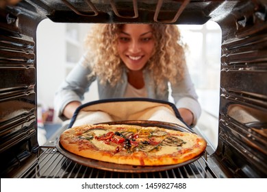 View Looking Out From Inside Oven As Woman Cooks Fresh Pizza