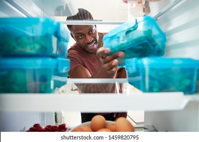 View Looking Out From Inside Of Refrigerator As Man Takes Out Healthy Packed Lunch In Container