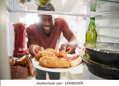 View Looking Out From Inside Of Refrigerator Filled With Unhealthy Takeaway Food As Man Opens Door