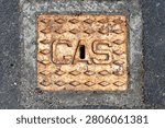 View looking straight down onto a rusty metal access plate to a gas stop valve embedded in a suburban street in Sandy Bay, Tasmania