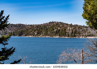 View Looking Towards The Lake Arrowhead North Shore With A Boat, Blue Sky, Green Trees, Hills And Blue Rippling Water