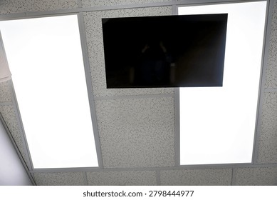 View looking upward toward a ceiling-mounted television and overhead lighting from a dental treatment chair in a modern dental office.