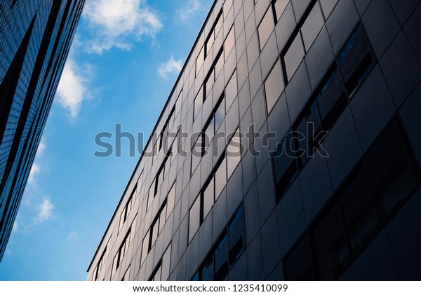A view from lower angle of a\
gap between two buildings with background  of clear\
sky.