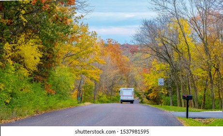 View Of Mail Truck Driving Down Colorful Suburban Street In Fall