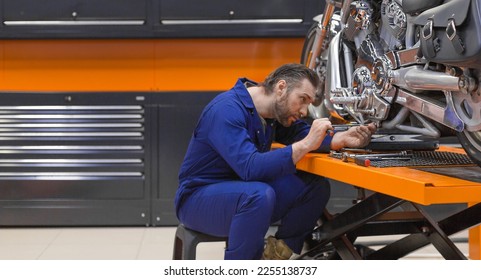 View of a man fixing a motorcycle raised on a lift in a modern workshop. - Powered by Shutterstock