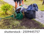 View of man loading top dresser with soil from plastic bag for lawn restoration in garden. Sweden.