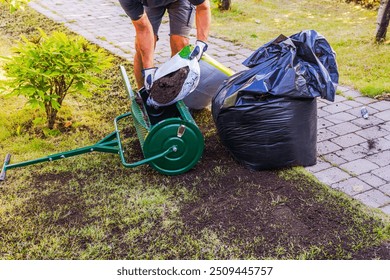 View of man loading top dresser with soil from plastic bag for lawn restoration in garden. Sweden. - Powered by Shutterstock