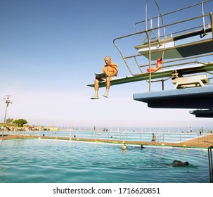 View Of Man Reading The Newspaper While Sitting On A Diving Board, Cape Town, South Africa