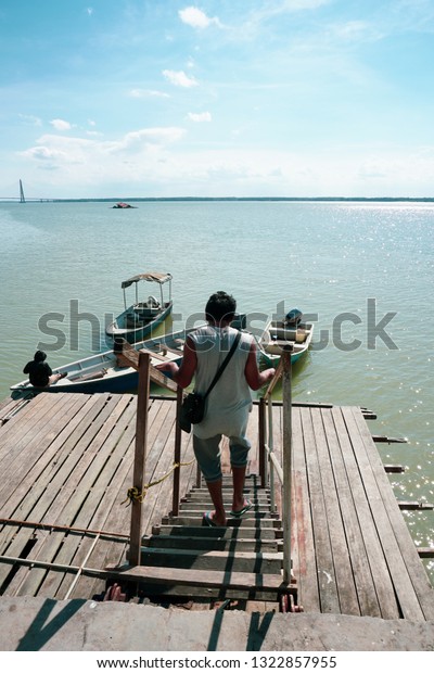 View of a man walking down the jetty stairs and a\
man tie a rope to secure his boat to a wooden jetty. view from a\
wooden jetty