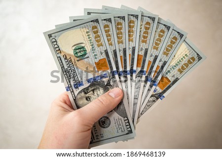 View of a man's hand holding a bundle of 100 dollar bills. Saving money concept