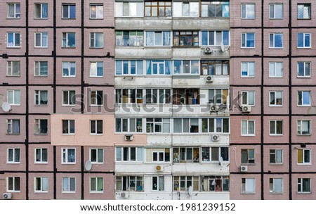 View of the many windows of apartments in a multi-storey Soviet-built residential building.  Close-up view.