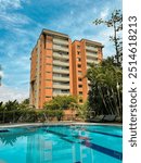 View of Medellin, Colombia. A building with a pool, surrounded by nature, trees, and a beautiful blue sky with clouds.