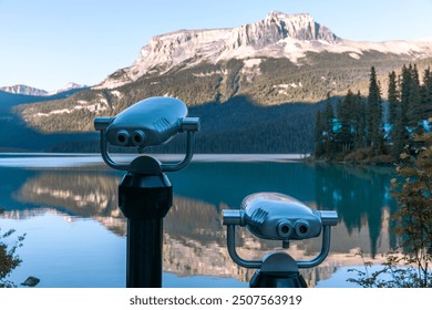 view of a metal binoculars in front of a mirror lake with mountains in the background in summer - Powered by Shutterstock