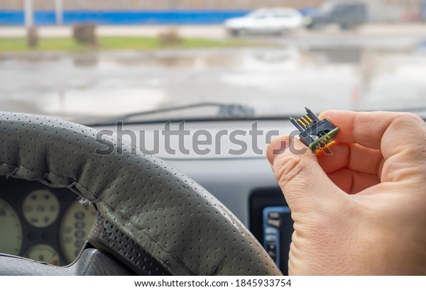 view of a microchip with electric gold\
plated contacts in the car driver\'s\
hand
