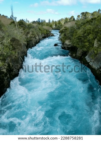 View of the mighty Huka Falls of the Waikato River with its beautiful blue-green aqua clear pool and foam near Taupo on the North Island of New Zealand.
