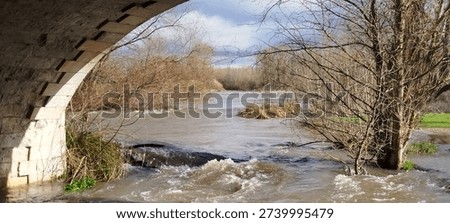 View of a mighty river through the arch of a stone bridge in Burgos, Spain