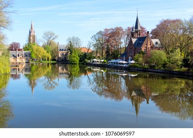 View at the Minnewater lake with reflections in the water and several historical buildings in the background in Bruges, Belgium.