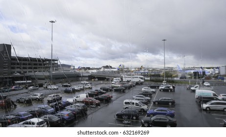 View From Mirror Of Airport Parking In Rainy Season Of Manchester, England With A Lot Of Car, Airplanes And Building.