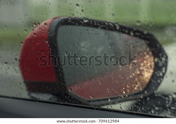 View mirror from inside of car on raining day with\
rain drop focus on