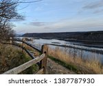 View of Mississippi River with wooden fence and Rocky trail with bluffs in background and dusk sky on top of Brady
