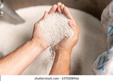View of modern factory worker hands holding pile of white polymer pellets