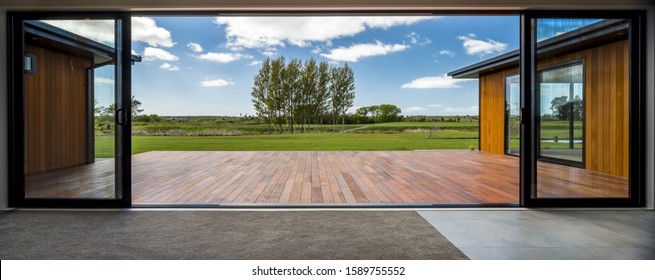 A view from a modern house with big glass doors looking at the green field