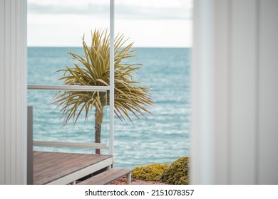 View From A Modern Summer Cottage Or House Or Glamping Towards The Sea. Bushy Palm Decoration In Focus.